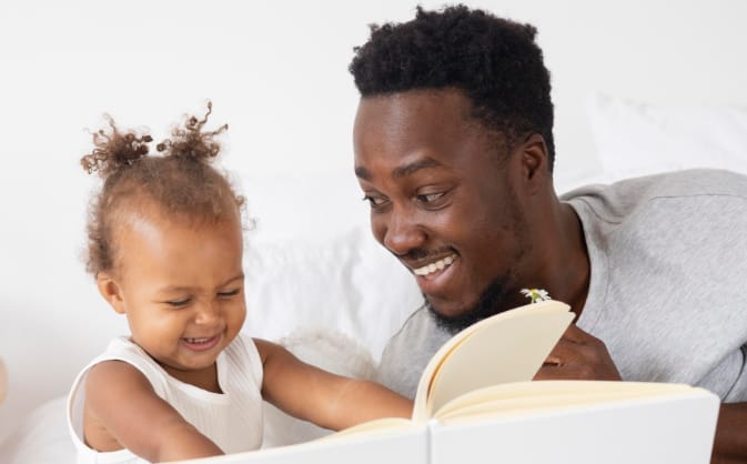 young father smiling alongside his toddler daughter