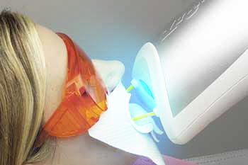 zoom teeth whitening unit in action shining a light on a prepared patients teeth